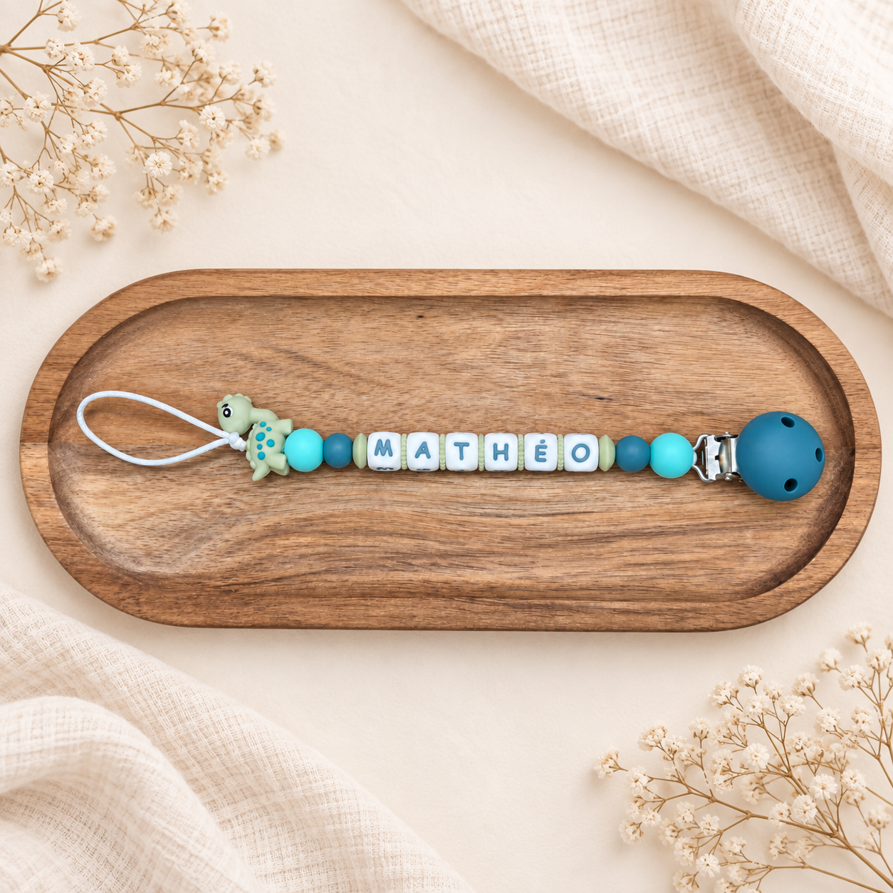 Attache-tétine personnalisée avec perles bleues et turquoise et décoration dinosaure